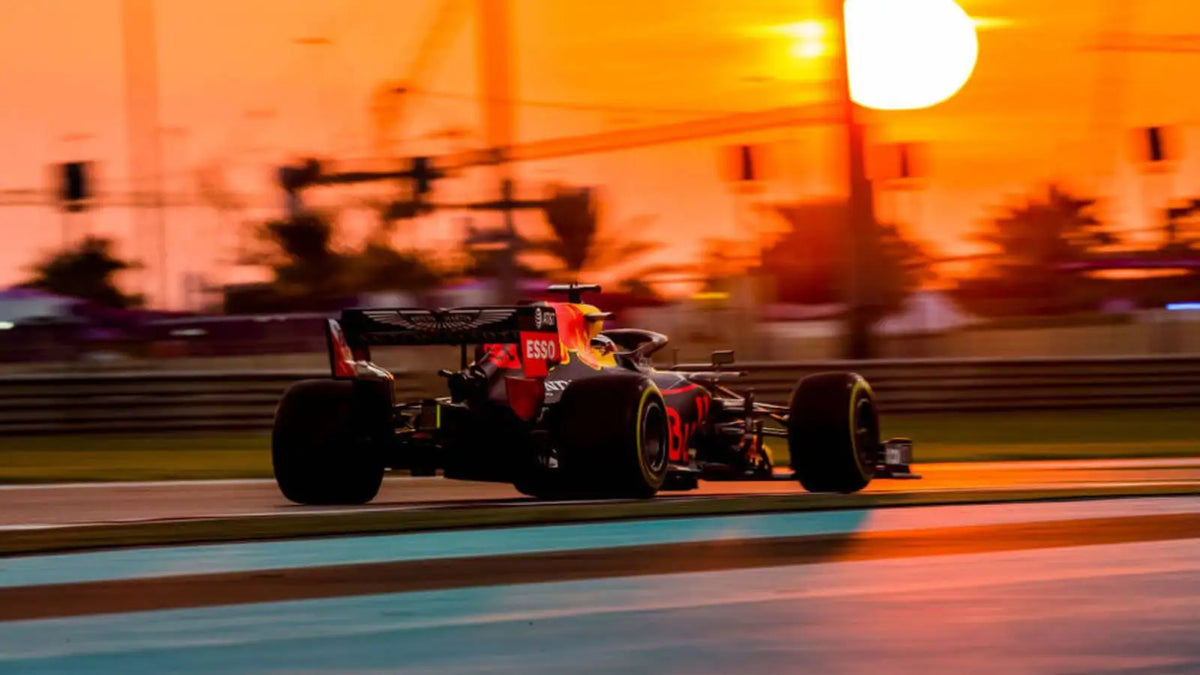 Red bull formula 1 race car speeding along the track at sunset.
